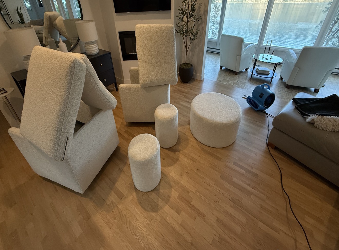Two white bouclé armchairs and ottomans fully cleaned and drying with air mover running, Kelowna living room