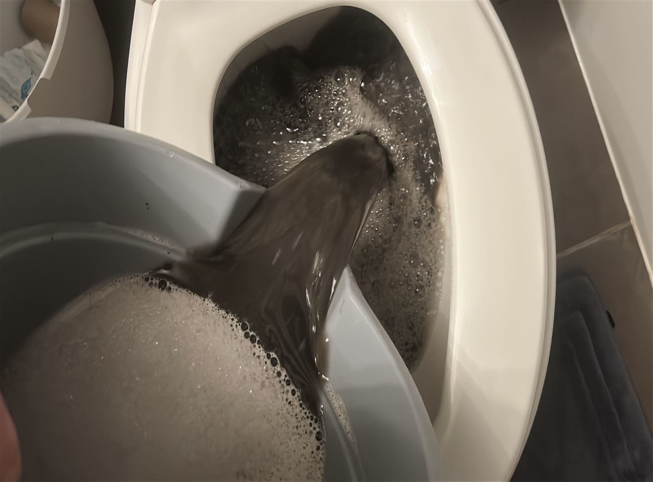 Dark dirty water recovered during hot water extraction of heavily soiled carpet