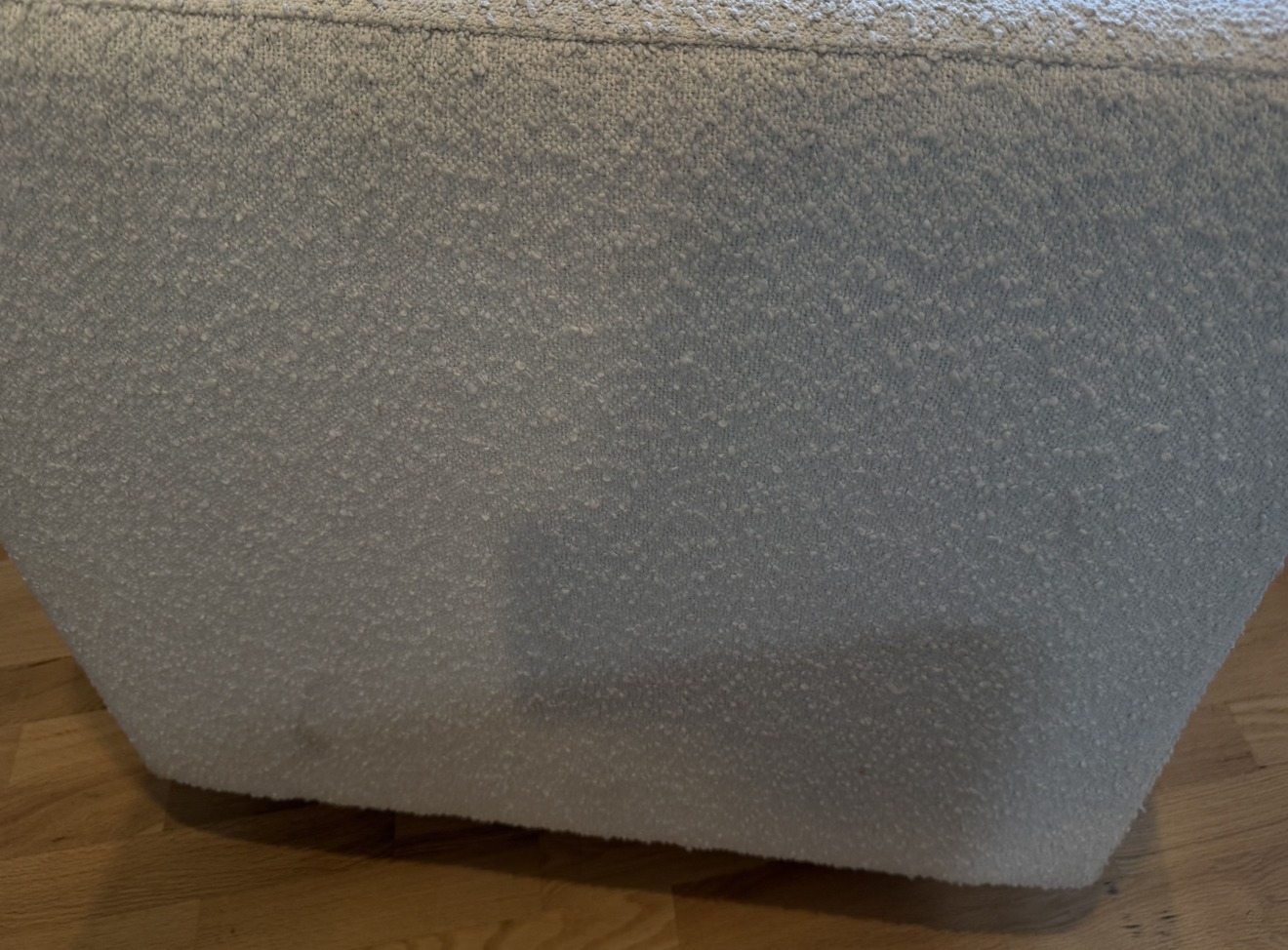 Close-up of white bouclé ottoman fabric showing heavy discolouration and soiling prior to professional cleaning in Kelowna