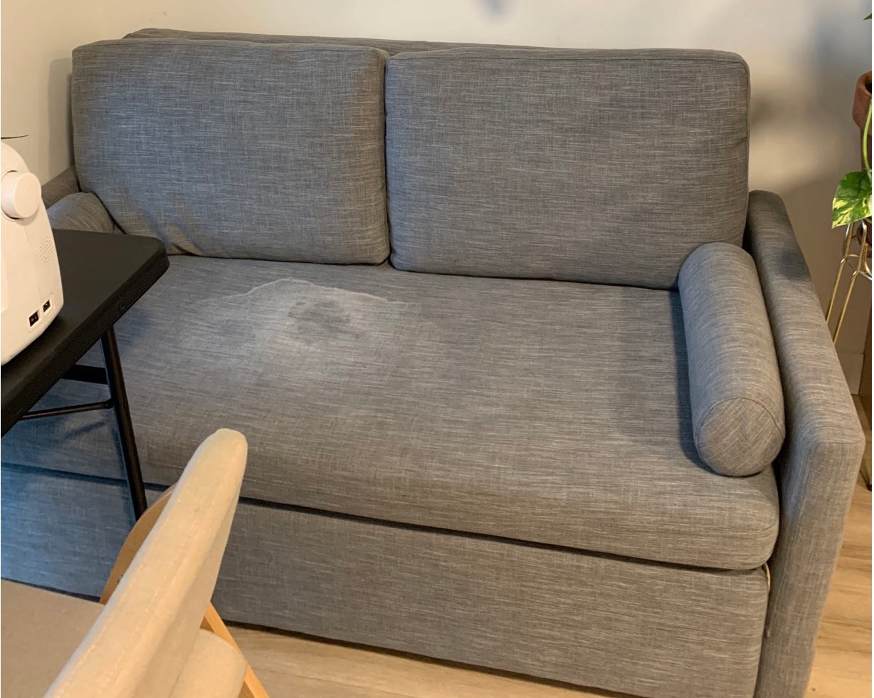 Love seat upholstery with blood stain and baking soda residue before professional cleaning in Kelowna