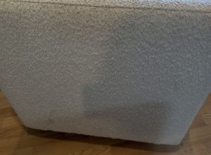 Close-up of white bouclé ottoman fabric showing heavy discolouration and soiling prior to professional cleaning in Kelowna